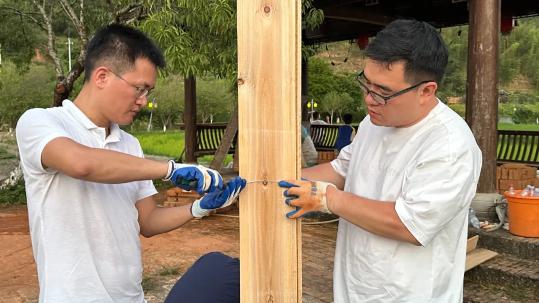 爸爸们合作将三块木板用铁丝固定在一起